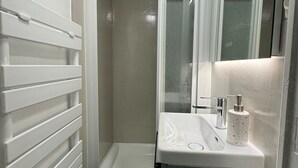 A bathroom with a shower, a sink, and a mirror. - L'escale (Rennes)