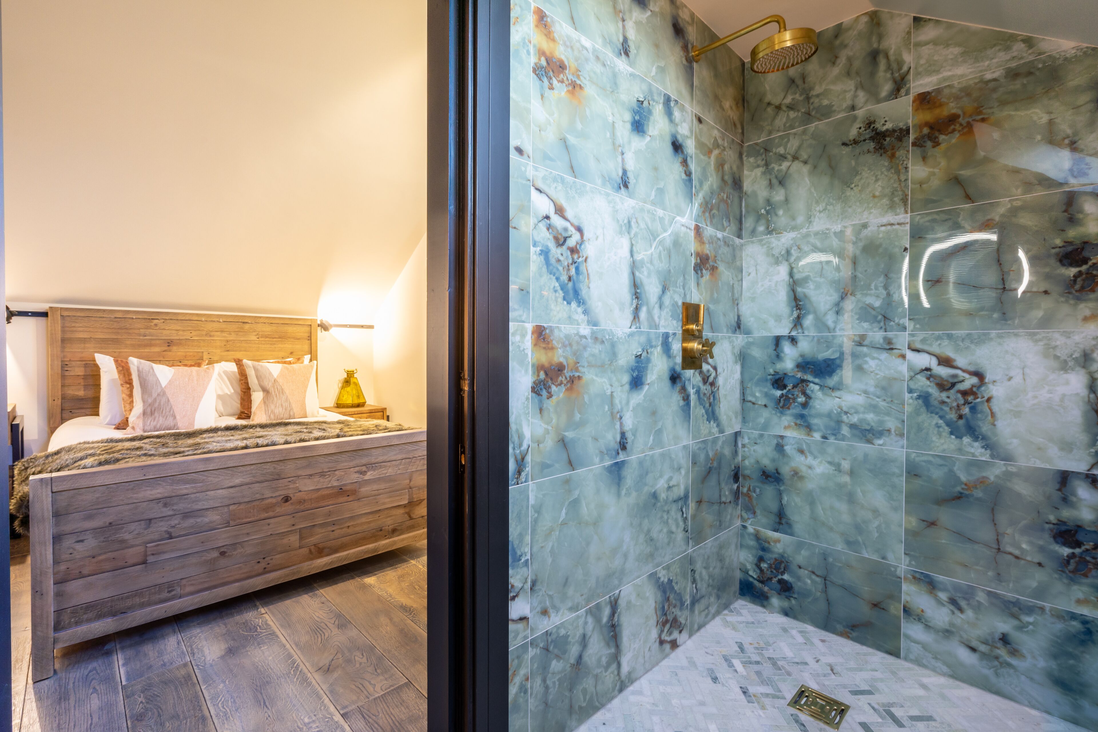Een slaapkamer met een houten bed en een badkamer met marmeren tegels.