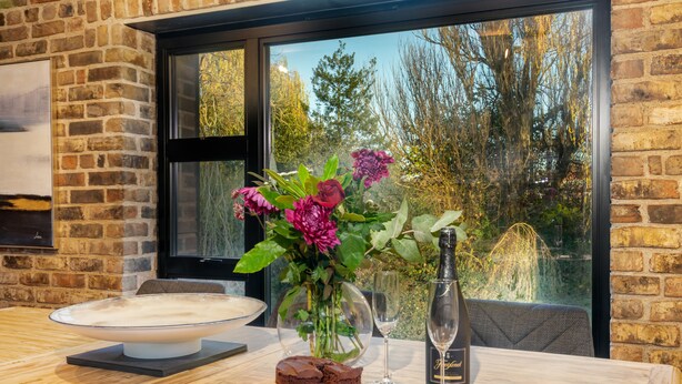Une table à manger avec un gâteau, un verre de vin et un vase de fleurs.