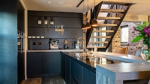 Une cuisine moderne avec des meubles de couleur sombre, un îlot central et un mur en briques.