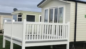 Een stacaravan met een wit terras en een kleine aangebouwde garage.