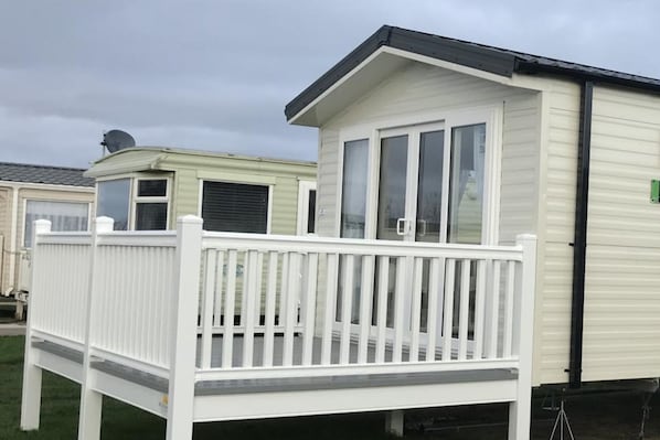 A mobile home with a white deck and a small attached garage.