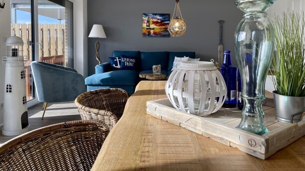 Una sala de estar moderna con un sofá azul, una lámpara blanca y un florero de vidrio decorativo.