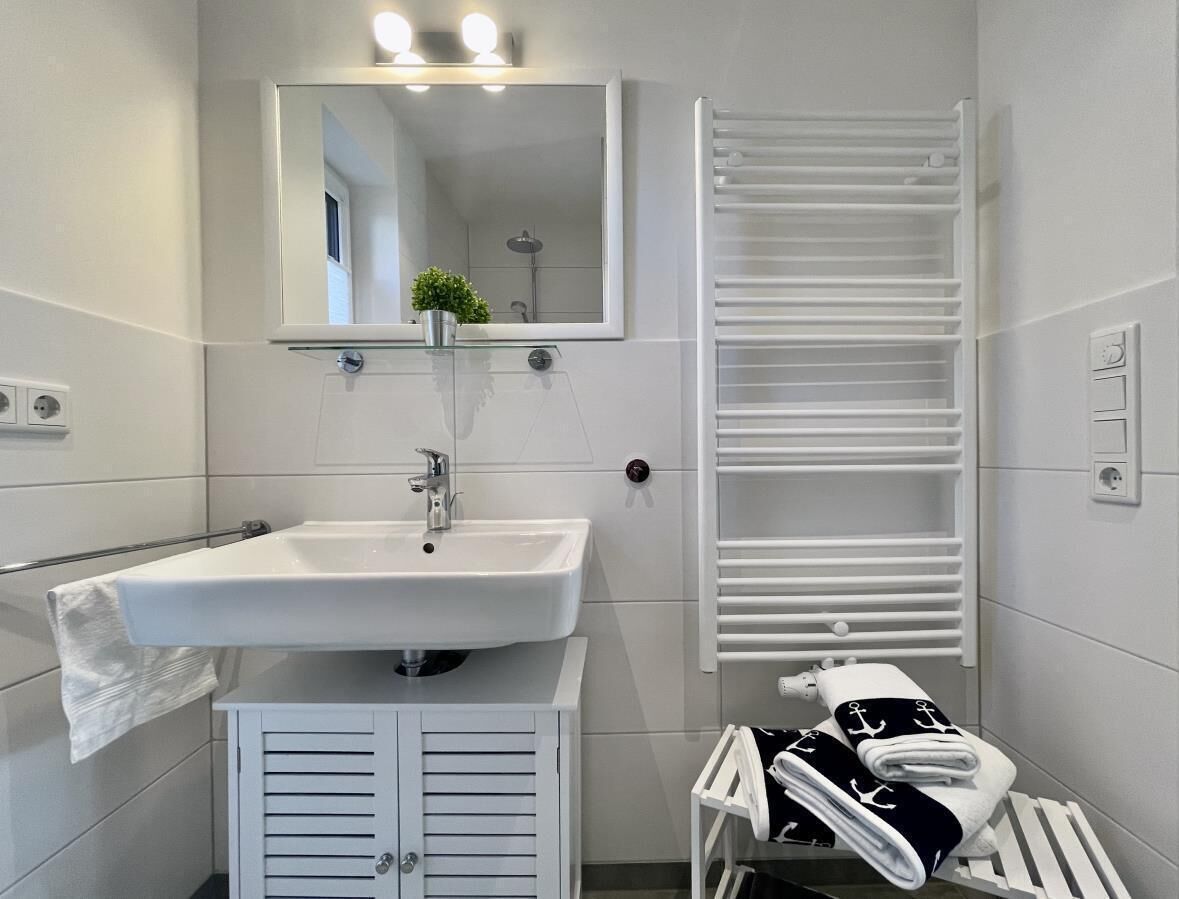 A modern bathroom with a white sink, mirror, towel rack, and a white towel.