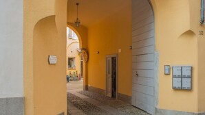 Un couloir étroit avec une grande porte en arc, une porte et une boîte aux lettres fixée au mur.
