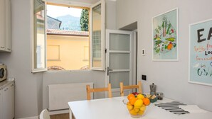 Une cuisine avec vue sur une montagne, une table à manger ornée de fruits et un meuble blanc.