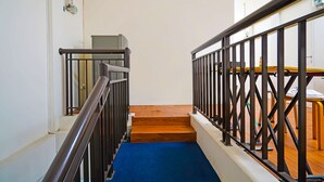 A staircase with a blue carpet, wooden steps, and black metal railings. - OYO Life 92720 Mekarwangi Guest House (Bandung)
