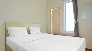 A neatly made bed with white linens in a room with a wooden floor, a window with curtains, and a door. - OYO Life 92720 Mekarwangi Guest House (Bandung)