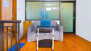 A room with a patterned sofa, a small table with a laptop, and a wooden floor. - OYO Life 92720 Mekarwangi Guest House (Bandung)