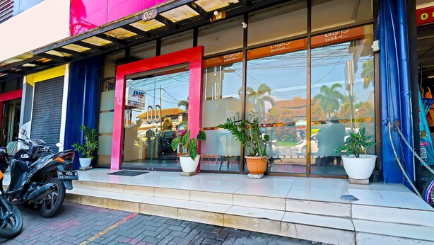 A storefront with a glass facade, potted plants, and a motorcycle parked outside. - OYO Life 92720 Mekarwangi Guest House (Bandung)