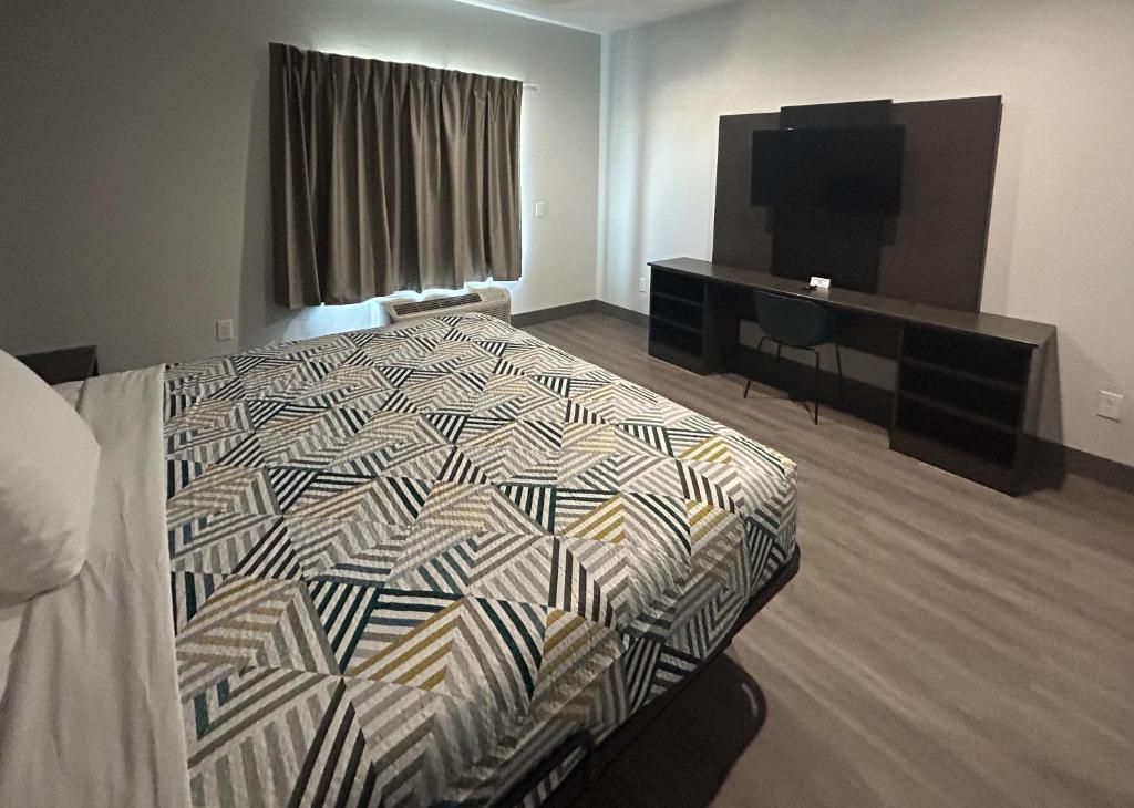 A hotel room with a bed, a desk, a chair, and a television.