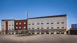 Un hôtel moderne doté d’un toit plat, de nombreuses fenêtres et d’une enseigne indiquant qu’il s’agit d’un Motel 6.