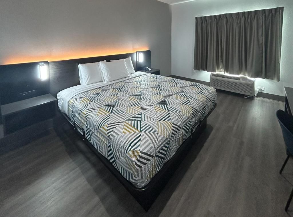 Una habitación de hotel moderna con una cama grande, una mesita de noche y un sistema de aire acondicionado integrado.