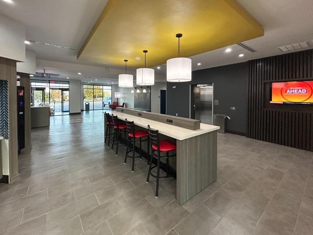 Un área de cocina moderna con una isla central, taburetes de bar e iluminación colgante.