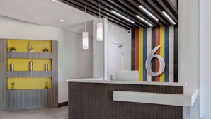 Un comptoir d’accueil au design moderne, un grand chiffre « 6 » peint sur le mur et un mur rayé aux couleurs vives derrière.
