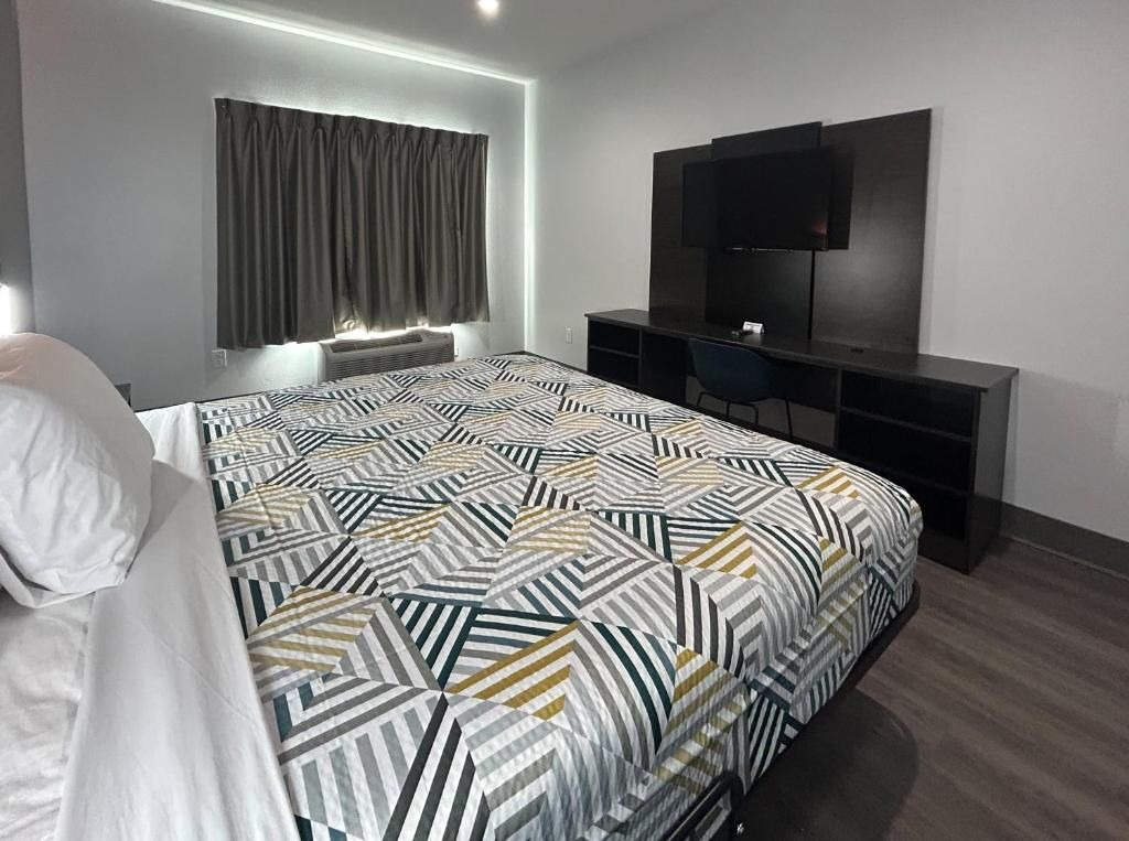 Quarto de hotel moderno com uma cama grande, uma escrivaninha e uma televisão de tela plana.