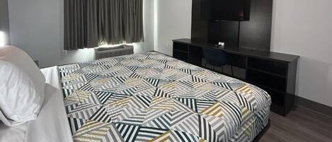 Quarto de hotel moderno com uma cama grande, uma escrivaninha e uma televisão de tela plana.