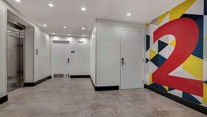 Un couloir moderne avec un grand chiffre « 2 » peint sur le mur, une porte et un ascenseur.