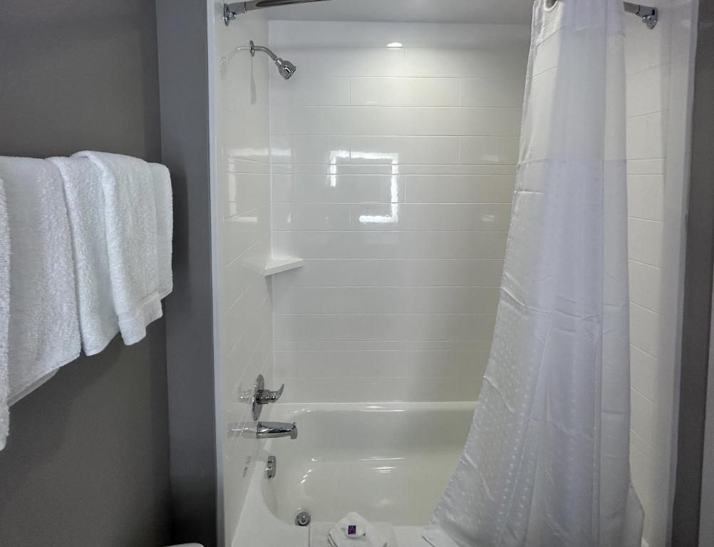 A bathroom with a bathtub, a shower curtain, and a towel rack with towels.