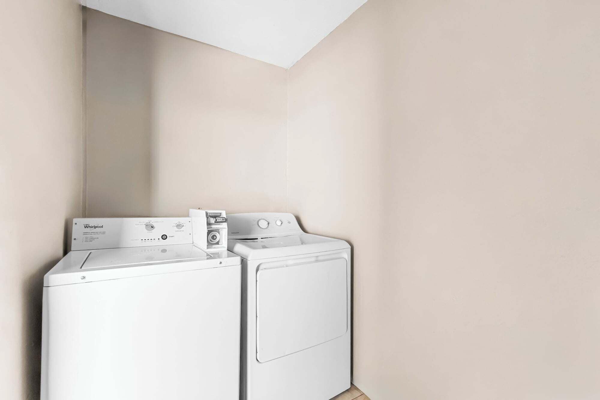 A laundry area with two Whirlpool dryers and a stacked washer and dryer unit.