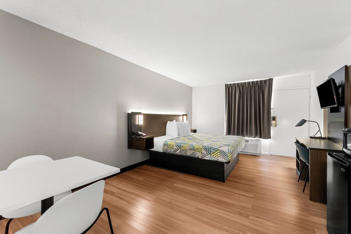 A modern hotel room with a bed, desk, and a TV.