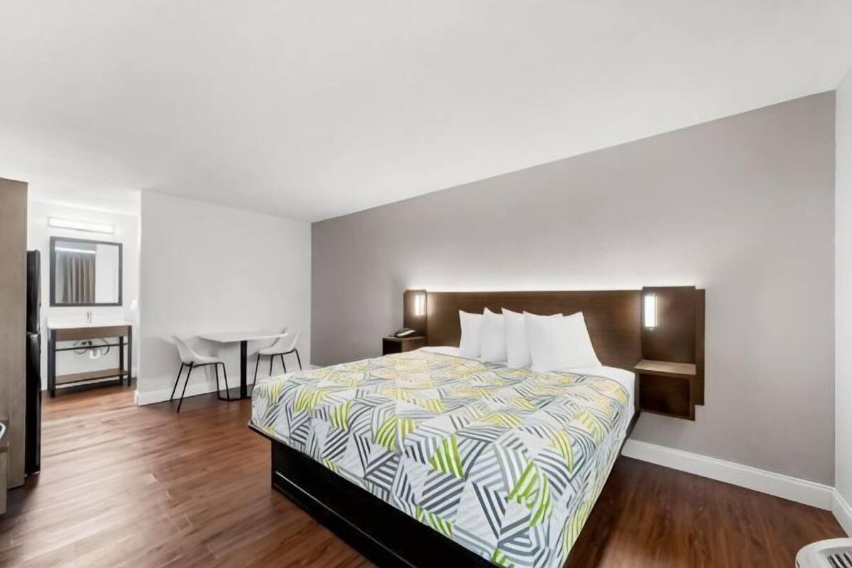 A bedroom with a bed, bedside tables, a desk, and a chair.