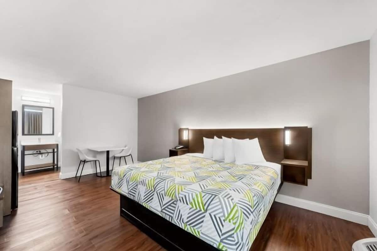Une chambre Ă coucher comprenant un lit, des tables de chevet, un bureau et une chaise.