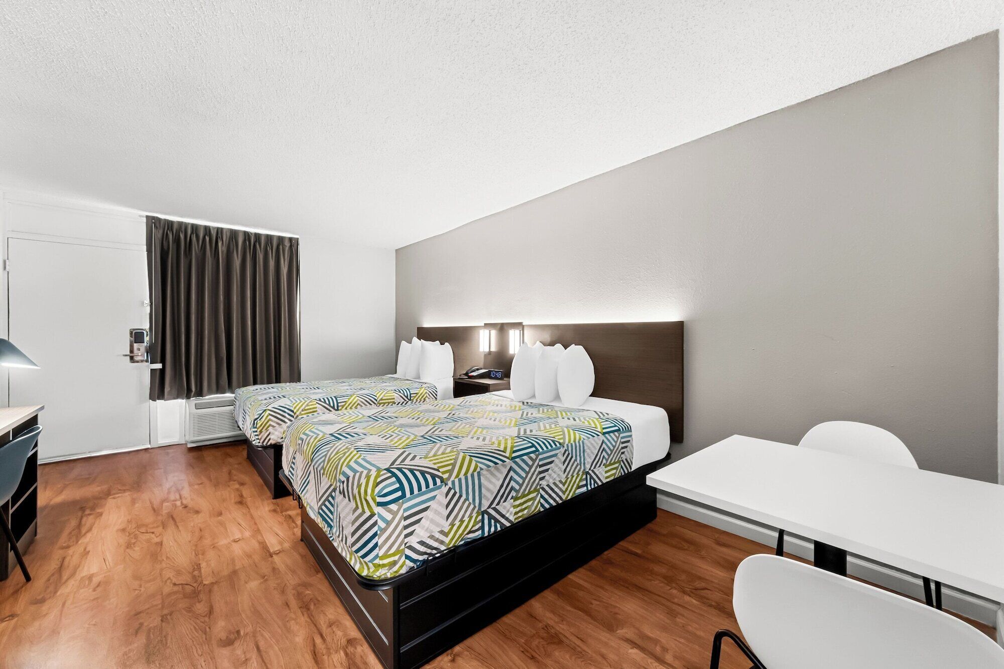 A modern hotel room with a large bed, a desk, and a chair.