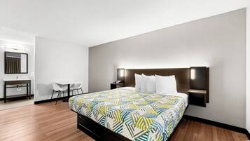 Une chambre d’hôtel moderne avec un grand lit, un bureau avec une chaise, une petite table et un miroir.