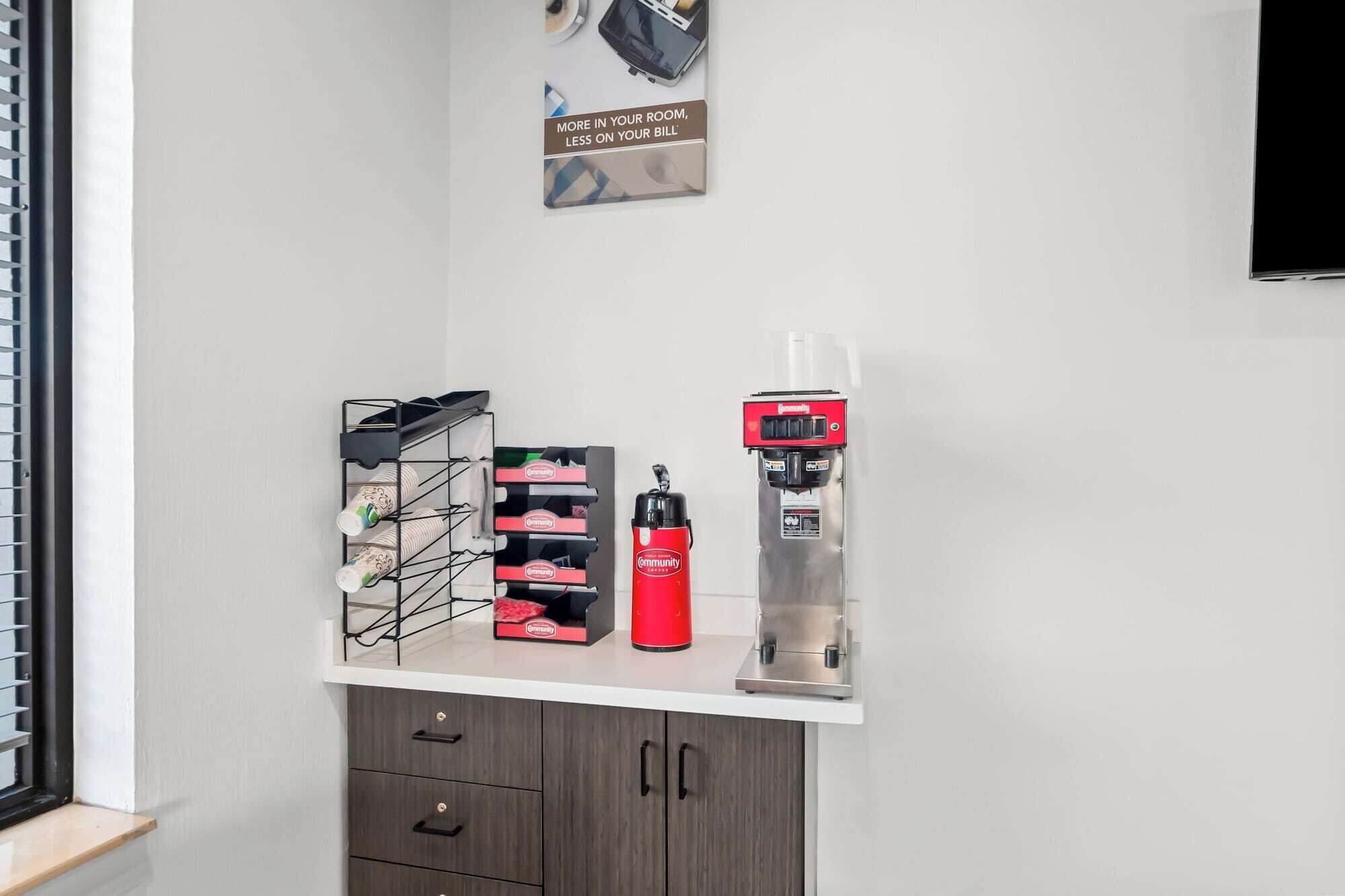 A kitchenette with a coffee machine, a red water dispenser, and a mug rack.
