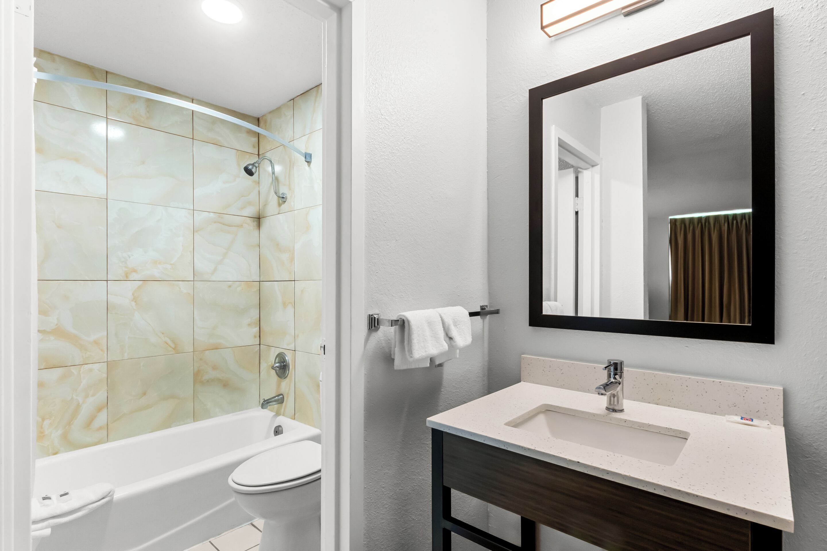 A bathroom with a bathtub, toilet, sink, and a mirror.