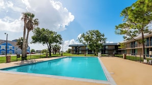 A swimming pool with a clear blue water, surrounded by a sandy deck. - Motel 6 Port Lavaca, TX (Port Lavaca)