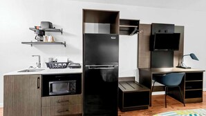 A compact kitchen with a built-in oven, a black refrigerator, a microwave, and a small sink. - Studio 6 Port Lavaca, TX (Port Lavaca)