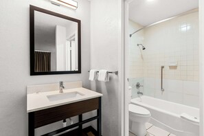 Een bad/douchecombinatie, handdoeken, toiletpapier