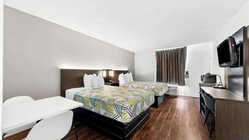 Habitación de hotel con dos camas, un escritorio, una silla, un televisor y una kitchenette.