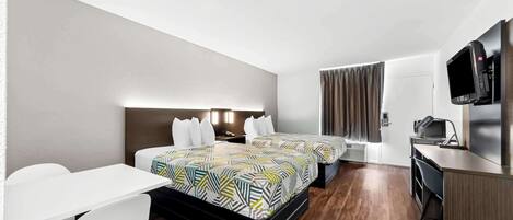 Habitación de hotel con dos camas, un escritorio, una silla, un televisor y una kitchenette.
