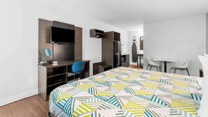 A modern hotel room with a bed, a desk, a chair, a TV, and a wardrobe. - Studio 6 Port Lavaca, TX (Port Lavaca)