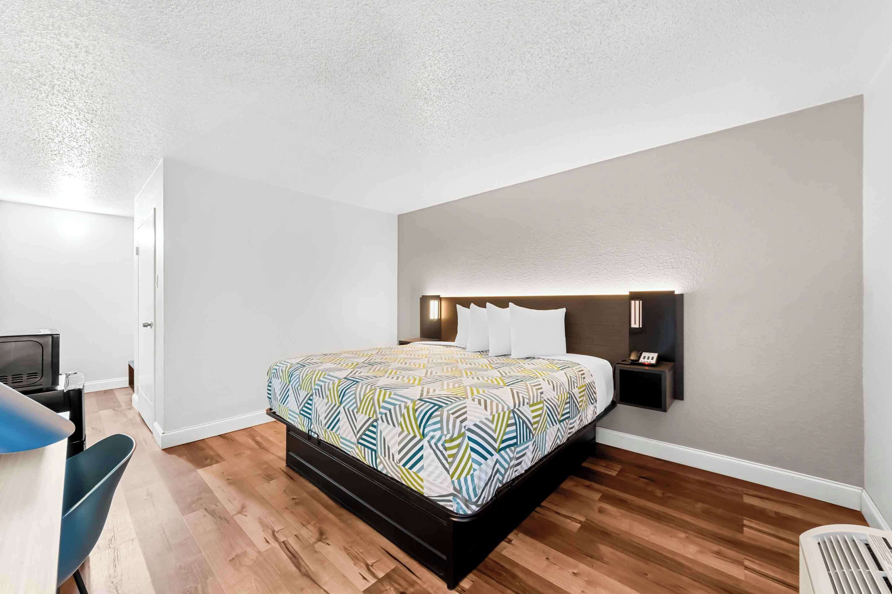 A modern bedroom with a large bed, a desk, and a chair.