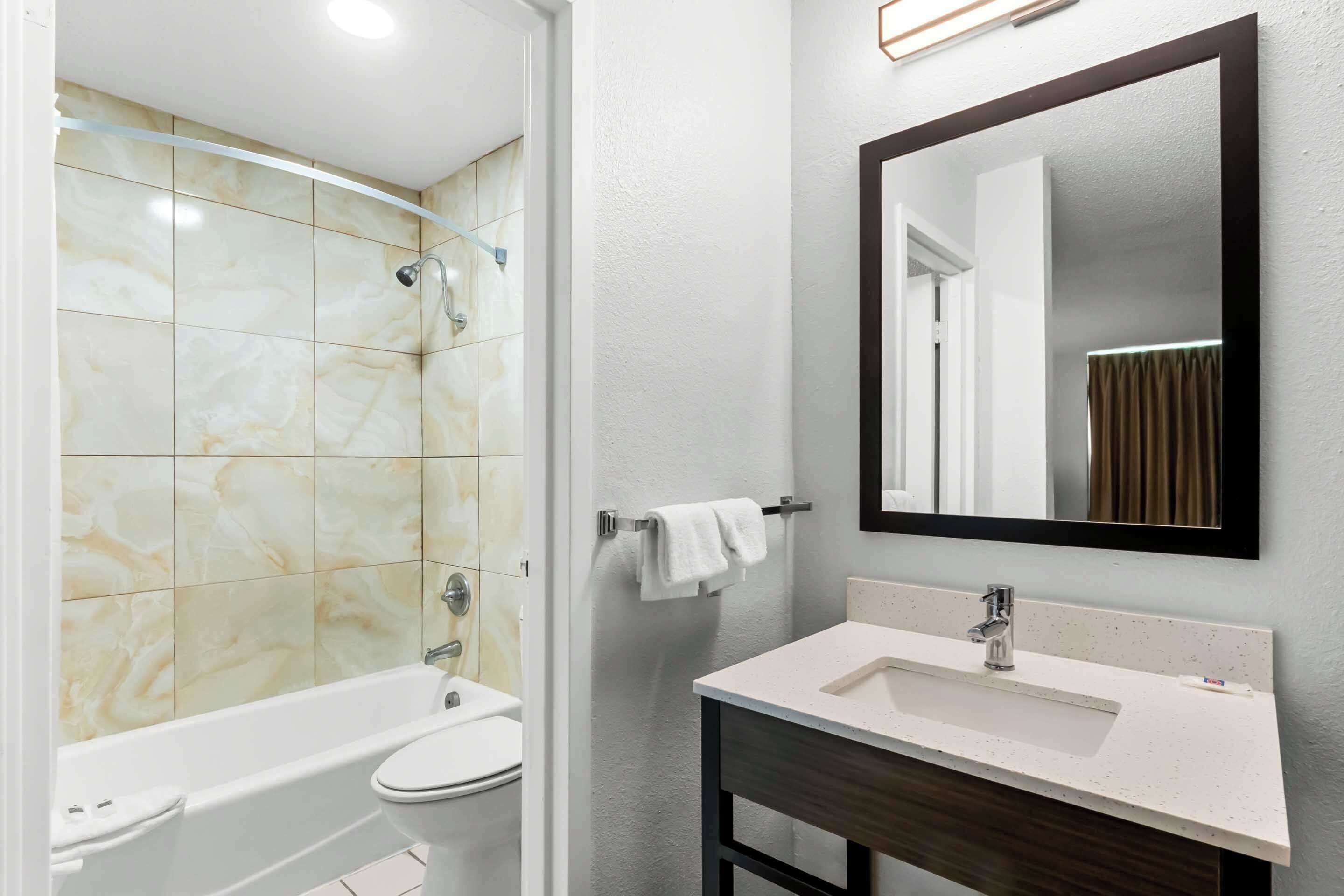 Une salle de bain équipée d’une baignoire, de toilettes et d’un lavabo, avec des carreaux de marbre et un grand miroir.