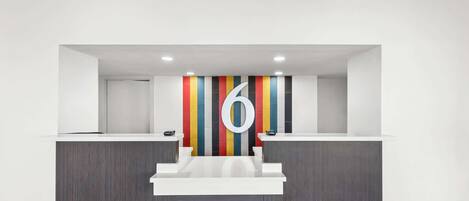 A reception area with a modern design, featuring a large number '6' on the wall, two reception desks, and a colorful striped wall behind them.
