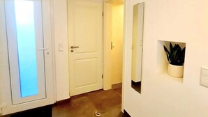 A hallway with a white door, a potted plant, and a wall-mounted mirror. - New Studio in Center (Luxembourg City)