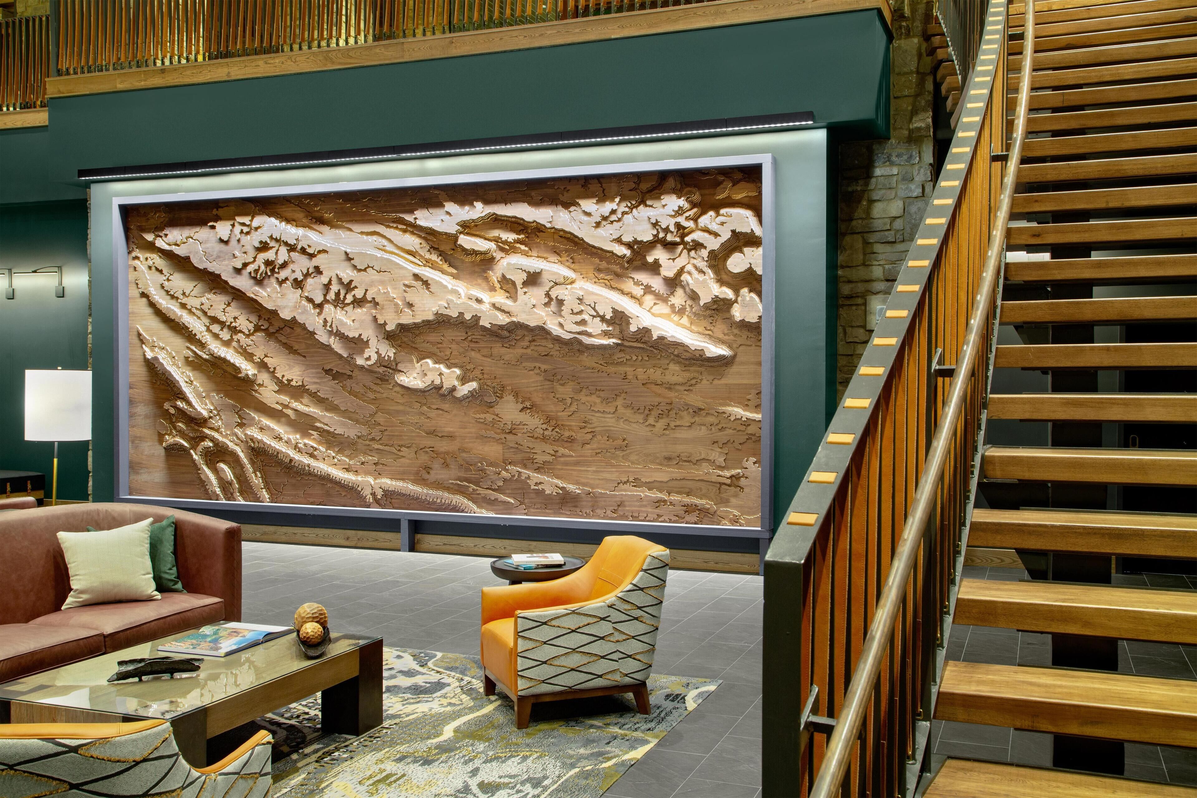 Un vestíbulo con un mural grande en la pared, una escalera, un sofá y una mesa de centro.