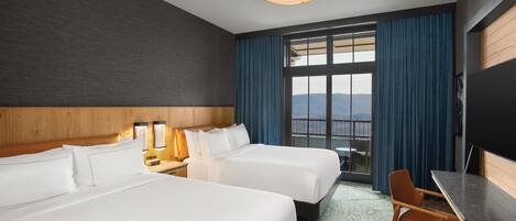 A hotel room with two beds, a desk, a chair, a TV, and a large window with curtains.
