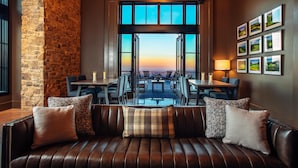 Un rincón acogedor con pared de piedra y vistas al atardecer a través de puertas abiertas.