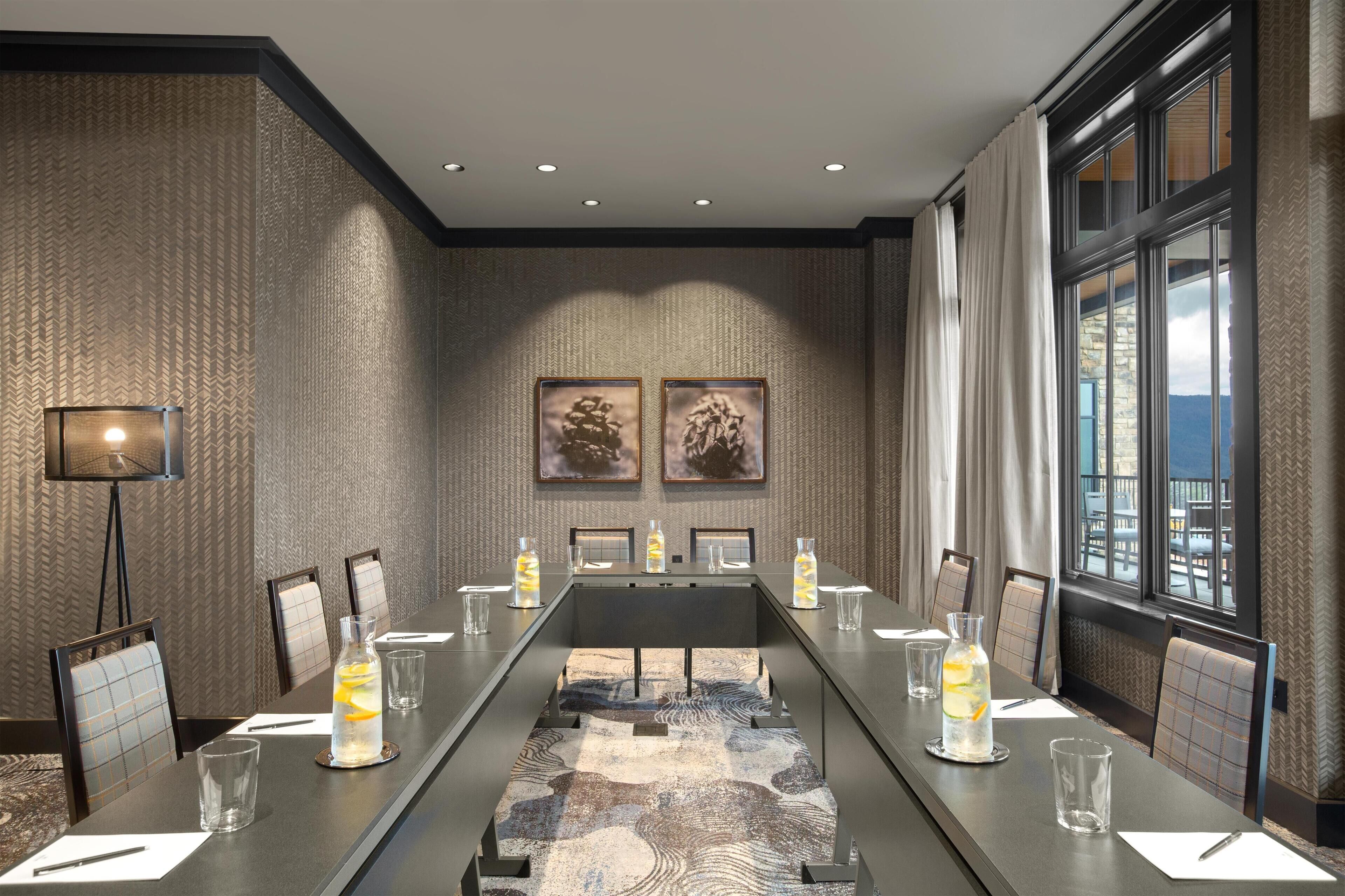 A conference room with a long table, chairs, and a large window.