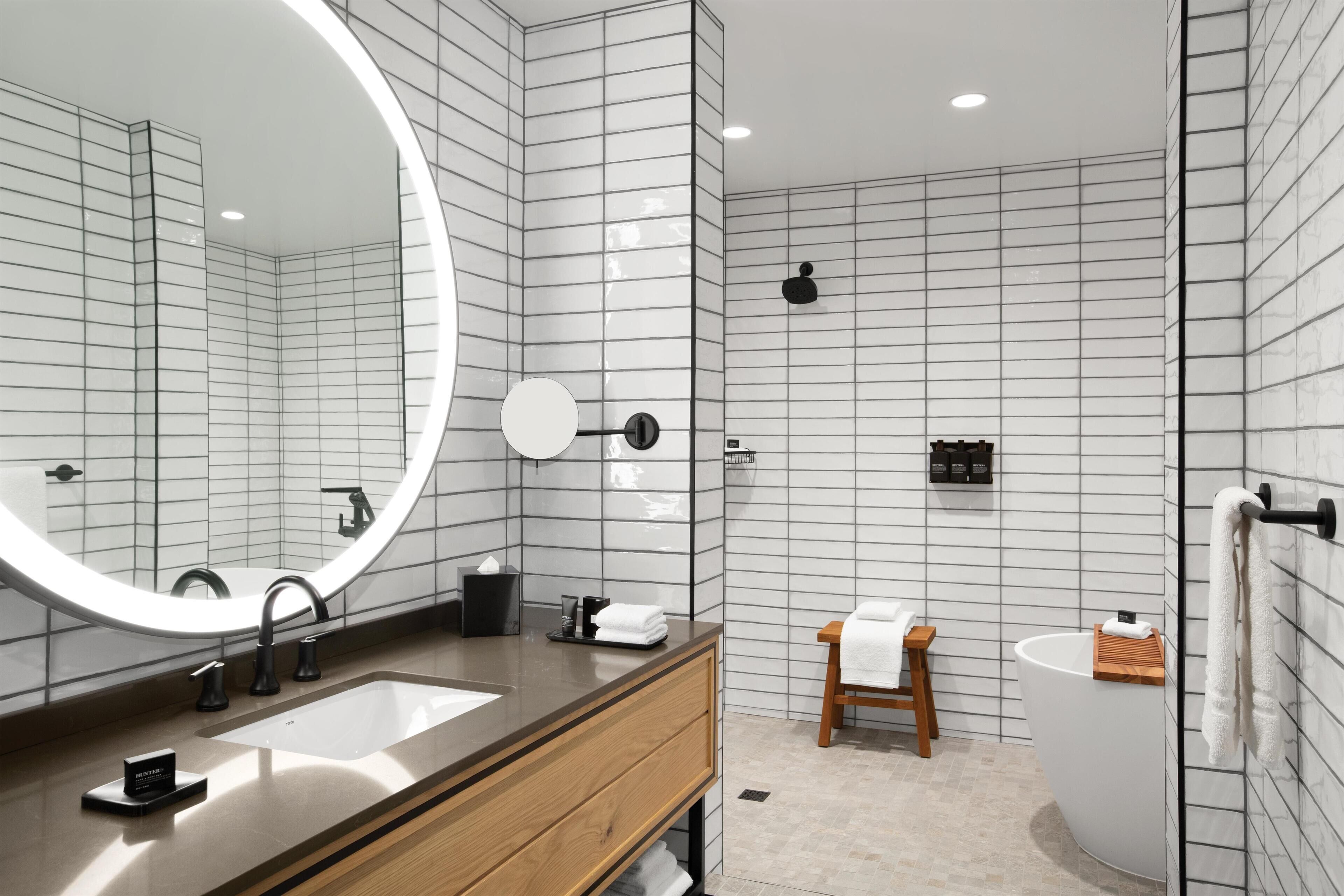 Une salle de bain moderne avec un grand miroir, deux lavabos, un meuble-lavabo en bois, des toilettes et une baignoire.