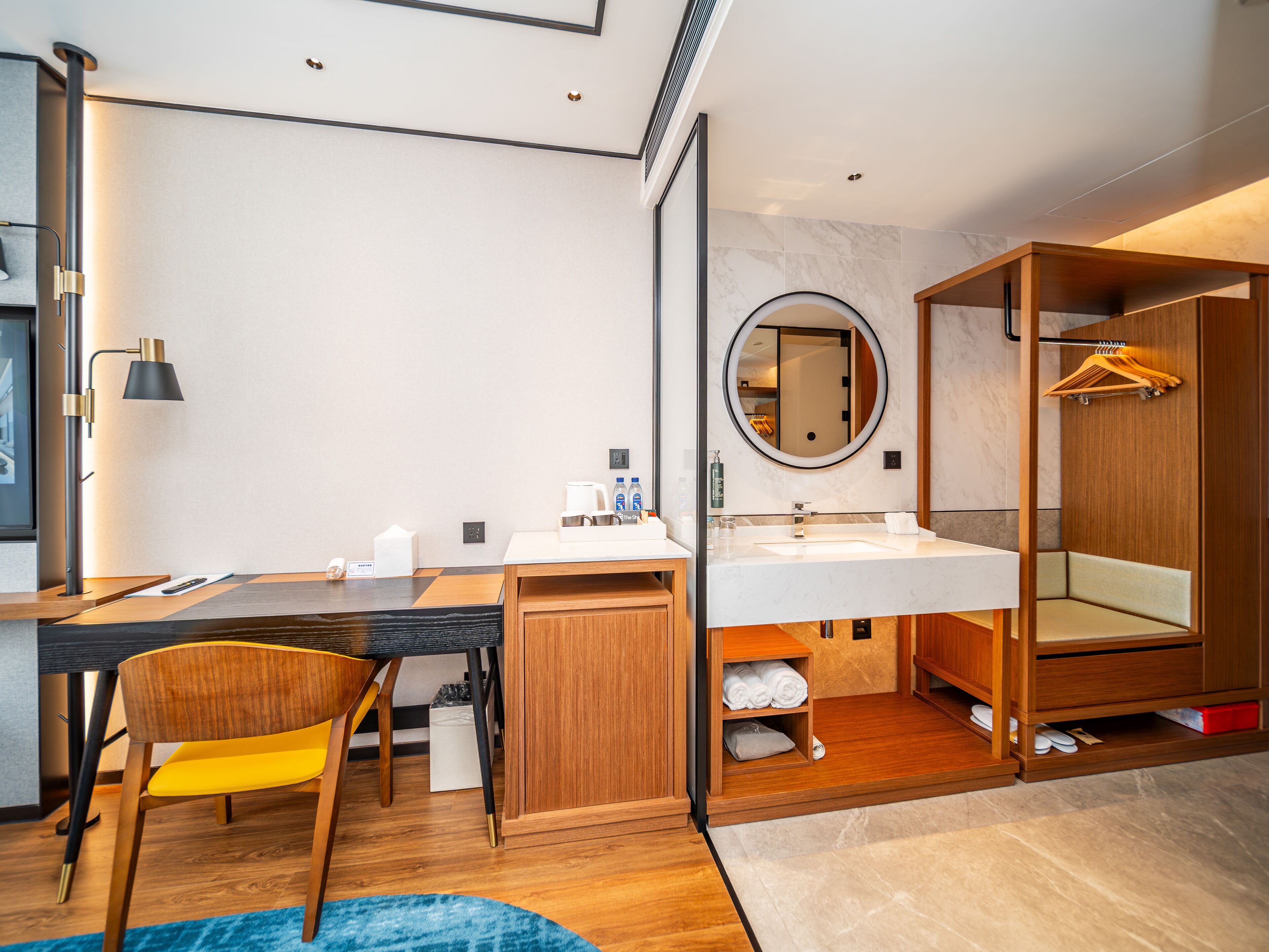 A modern bathroom with a wooden vanity, a round mirror, and a built-in shower area.