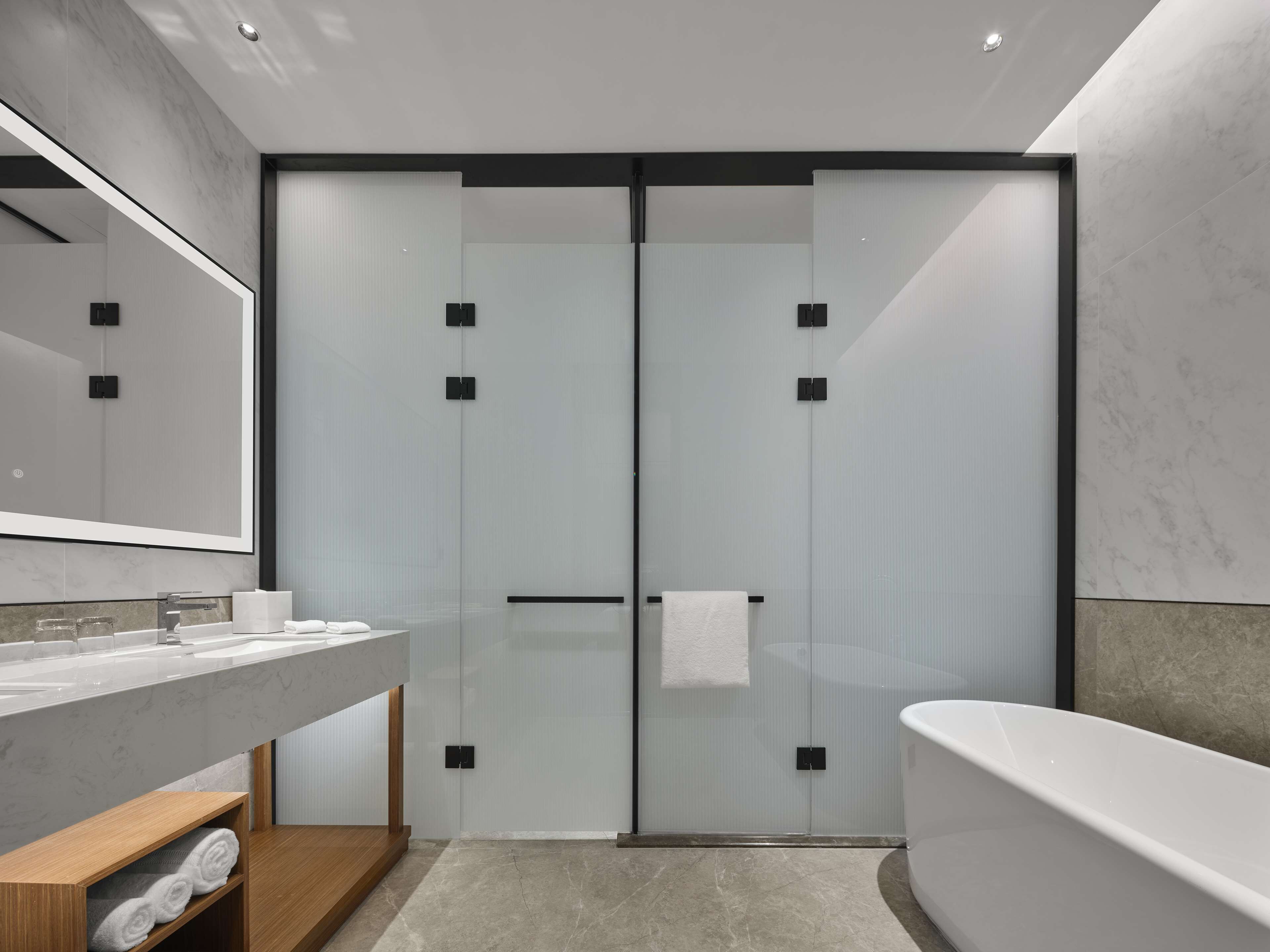 A modern bathroom with a large mirror, a bathtub, and a glass shower enclosure.