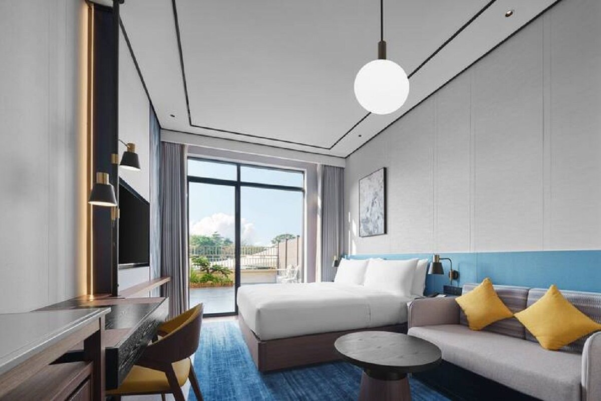 Habitación de hotel con una cama, un sofá, un escritorio y vistas al exterior.