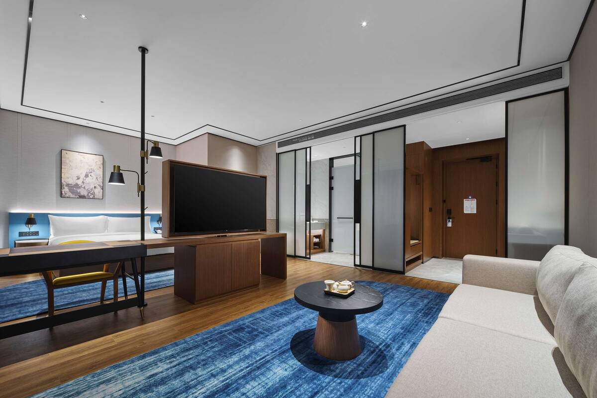 Una sala de estar moderna con un televisor de pantalla plana, muebles de madera y un tapete azul estampado.